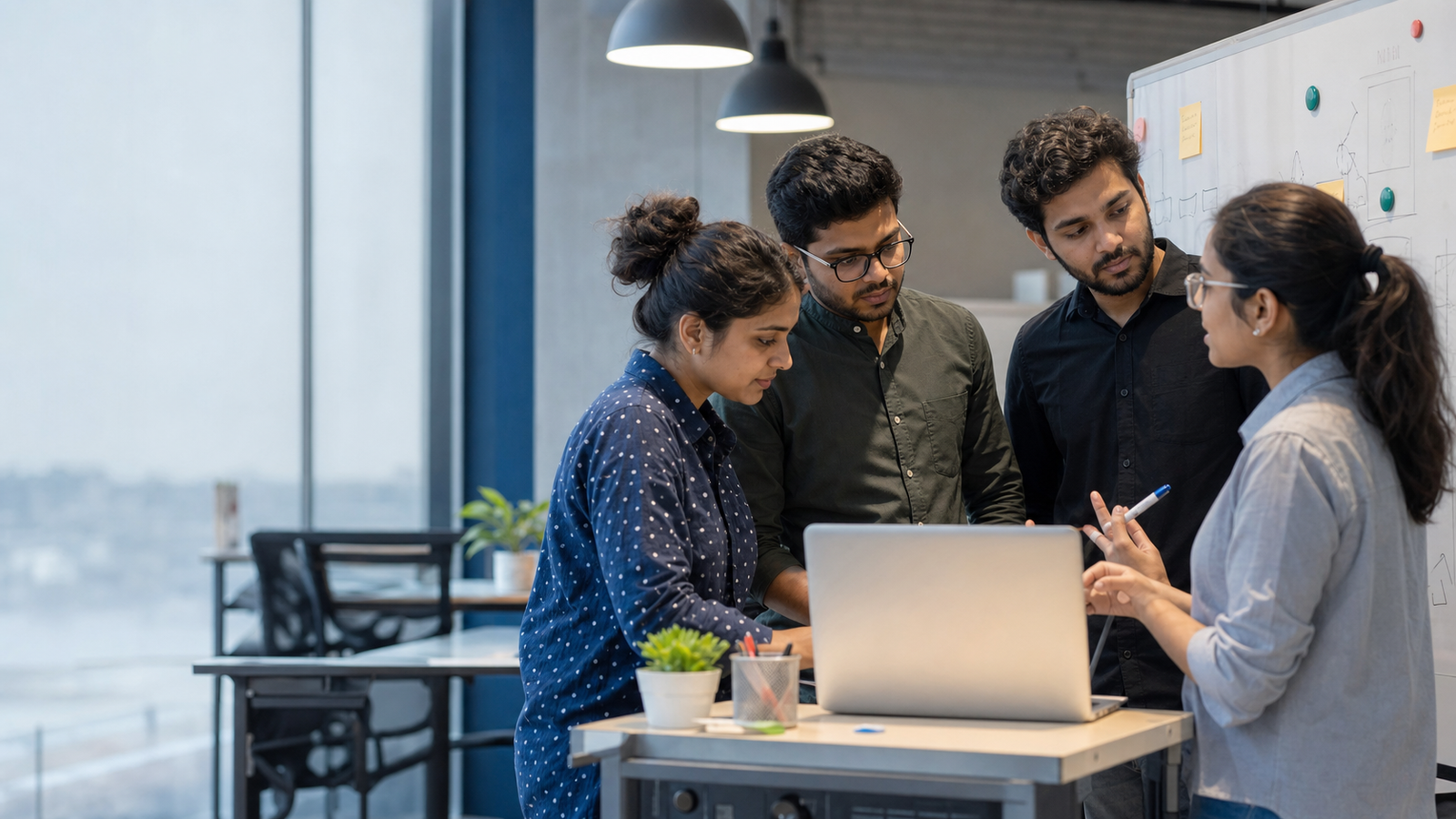 Indian product team collaborating around a laptop and whiteboard